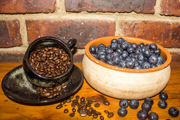 a rustic bowl with a few bright red strawberries, on top of a large amount of indigo-colored blueberries