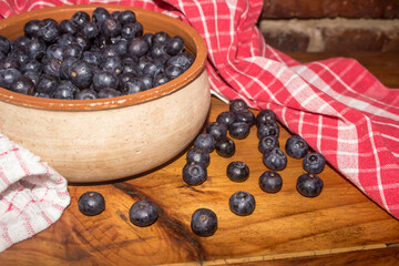 Bowl of Blueberries, some spilled out over a wooden tabletop