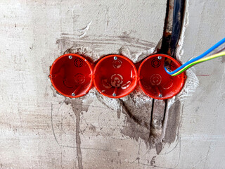 Wall-mounted wire setup for future outlets in a concrete wall. Concept of apartment build, raw...