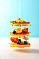Delicious Stack of Pancakes with Berries, Banana, and Syrup on Bright Blue Background