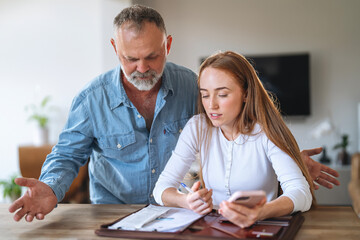 Discussion between a man and a woman at a home office as they review documents and communicate over...