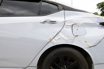 Broken car side mirror after accident, white vehicle with damaged wing mirror and raindrops on door...