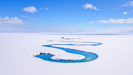 Obraz premium Aerial View of a Winding River Flowing Through a Snow-Covered Landscape Illustrates the Contrast Between Water and Ice in a Winter Wonderland