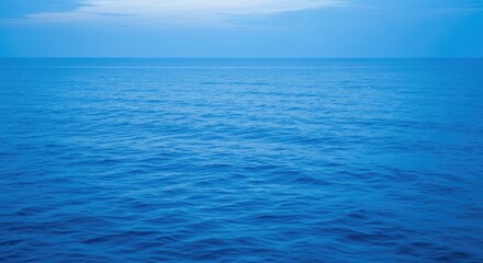 Obraz premium Serene blue ocean waves under cloudy sky at sunset