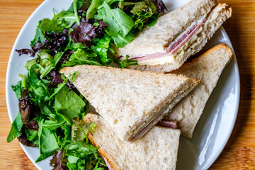 Homemade Ham and Cheese Sandwich In Sliced Brown Bread With Green Salad Leaves