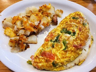 A hearty vegetable omelette, served alongside crispy hash browns on a white plate