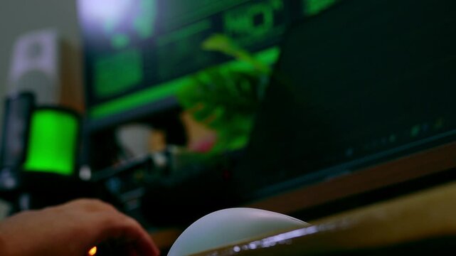 Slow motion shot of a hand typing on a keyboard in a dark hacker-themed setup with green code glowing on screens, creating a cinematic cyberpunk atmosphere.