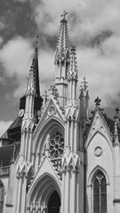 Tall church spire touches the sky with dramatic clouds in the background on a sunny day