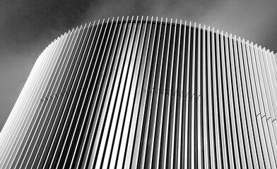 Curved façade element with light-colored parallel slats. Black and white image with strongly...