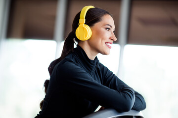Young athletic woman wearing yellow headphones at the gym, enjoying music during her workout for...