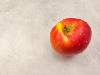 Fresh red apple resting on a textured surface