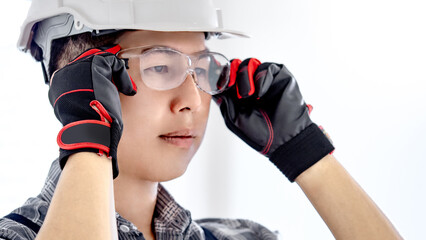 Headshot of Asian male construction worker or professional builder with helmet and leather gloves...