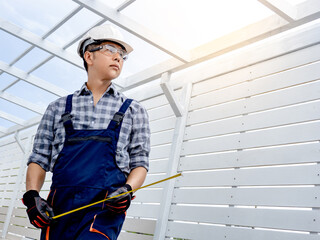 Portrait of Asian man civil engineer with safety helmet and goggles holding tape measure at...