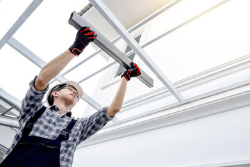 Asian man construction worker in protective workwear installing steel beam at building site. Male...