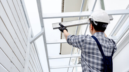 Roof installation process. House extension and renovation. Male roofer in protective workwear...