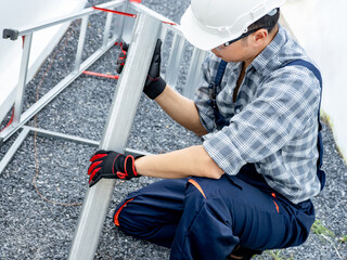Asian man construction worker in protective workwear picking steel beam up. Home builder working...