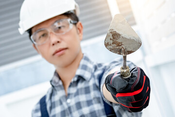 Plastering work tool. Asian man worker wearing protective safety helmet, goggles and gloves holding...