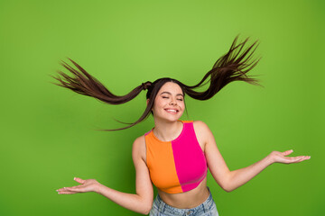 Playful young woman with unique hairstyle posing confidently against a vibrant green backdrop...