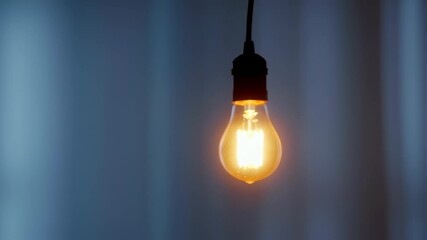 Closeup of Illuminated Edison Style Light Bulb Hanging in Dark Room with Warm Glow - Powered by Adobe