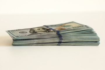 A neatly stacked stack of hundred dollar bills, close-up, side view, on a white background. This...
