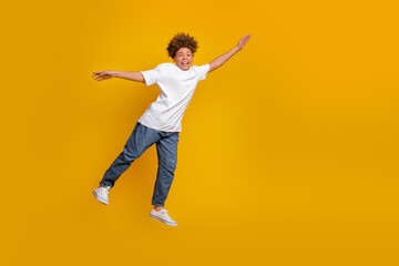 Cheerful boy expressive in a casual style white t-shirt and jeans on vibrant yellow background...