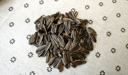 A handful of sunflower seeds on floral linen background 