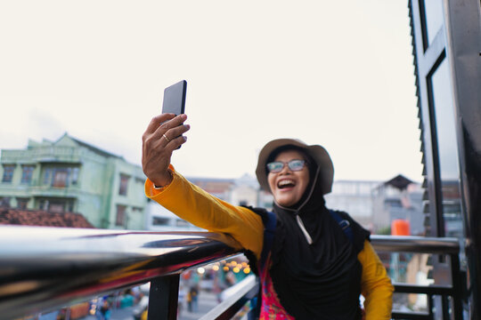 Smiling Woman Taking a Selfie Outdoors at Teras Malioboro in Sunny Day