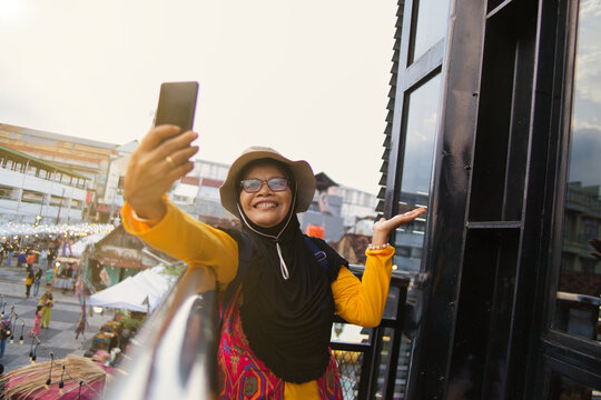 Smiling Woman Taking a Selfie Outdoors at Teras Malioboro in Sunny Day