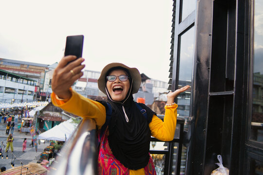 Smiling Woman Taking a Selfie Outdoors at Teras Malioboro in Sunny Day