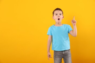 Portrait of surprised boy on orange background, space for text