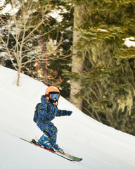 Close up cute little brave unrecognizable boy ski downhill on slope in winter ski resort. Active...