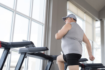 Man running on treadmill in gym. Mature male running on treadmill machine. Fitness, gym and exercising