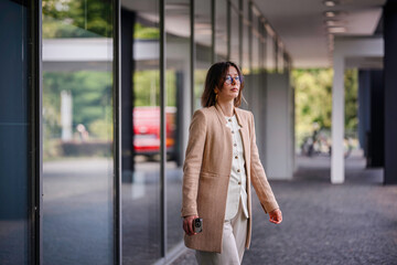 Confident Businesswoman Walking Outdoors with Phone in Hand