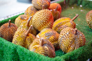 A pile of durian fruits in a green container are displayed at a market stall in Asia