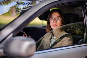 Woman Wearing Seatbelt and Holding Phone in Car