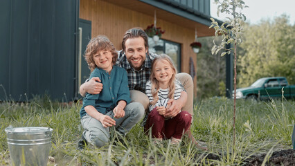 Happy Caucasian family having leisure day in garden. Bearded father hugging his lovely children...