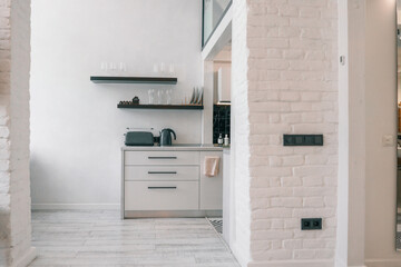 Modern minimal kitchen interior with black appliances, open shelves, and white brick wall. Stylish,...