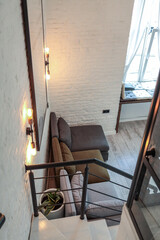 White painted staircase with black metal railing, descending into a bright living room with white...