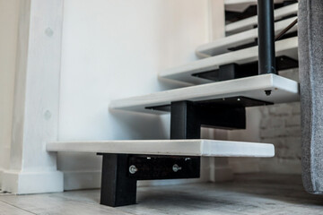 Close-up of modern minimalist staircase design with white wooden steps and black metal supports....