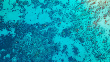 A stunning aerial view of a tropical coastline featuring lush green forest, a vibrant turquoise coral reef, and deep blue ocean waters. the natural beauty of marine and coastal ecosystems.