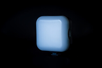 A square LED panel with soft light is displayed on a dark background. The panel emits a cool light...