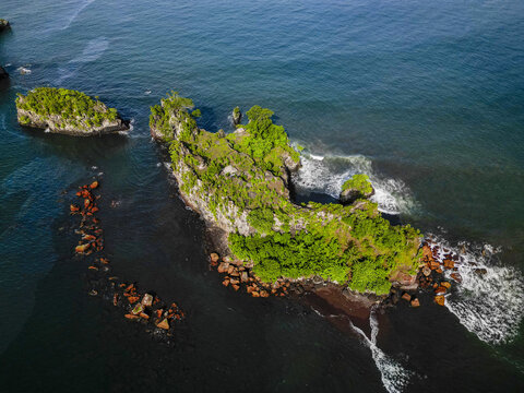 Aerial view of Bota Island's rugged coastline meets the Limbe River, its dark volcanic sands contrasting with the lush green vegetation, Limbe, South West, Cameroon.