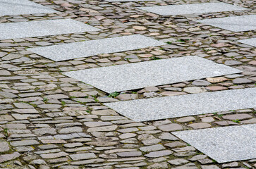 Modern granite crosswalk slabs integrated with historic cobblestone pavement, creating a unique...