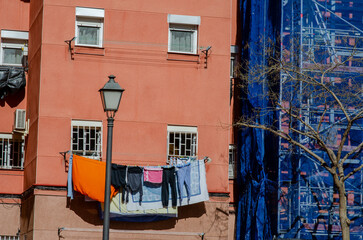 Bright city apartment building with vibrant clothes drying on a balcony, showcasing everyday urban life and neighborhood atmosphere.