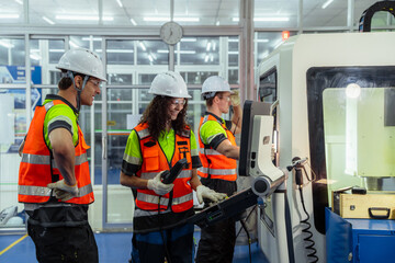Three people wearing safety gear. Female instructor training new workers or apprentices on how to...