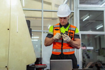 A man in a safety vest is working on a machine. Machinist or CNC machine operator setting up a...
