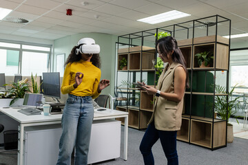 Diverse coworkers testing VR headset and using smartphone in open-plan office, copy space