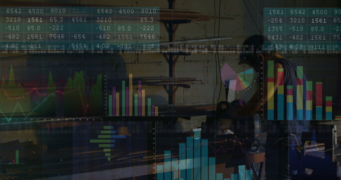 Operating welder in apron grinding pipe on bench in metal shop, with data charts, copy space - Powered by Adobe