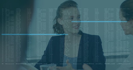Businesswomen analyzing data overlay at office conference table, with coffee mugs and laptop