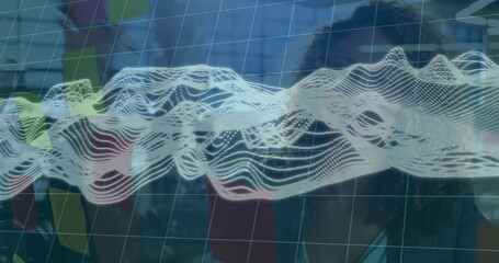 Two women wearing suits studying waveform, grid overlay on glass panel in office, with sticky notes